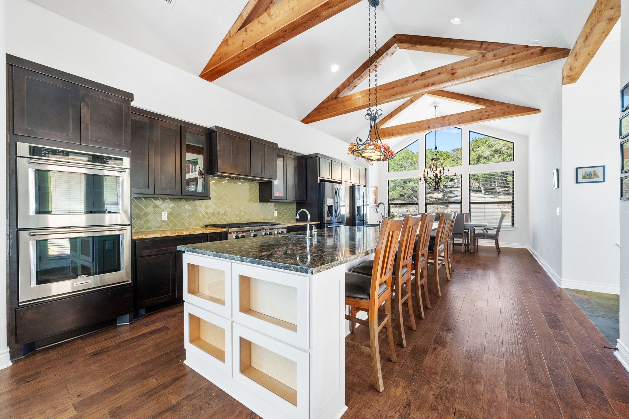 20607 Thurman Bend Road Spicewood, TX 78669 - Photo 8 of 39 a kitchen with stainless steel appliances granite countertop a stove a refrigerator a microwave a dining table and chairs with wooden floor