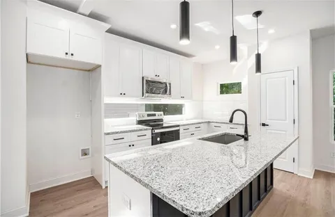 a kitchen with granite countertop a sink a counter space appliances and cabinets