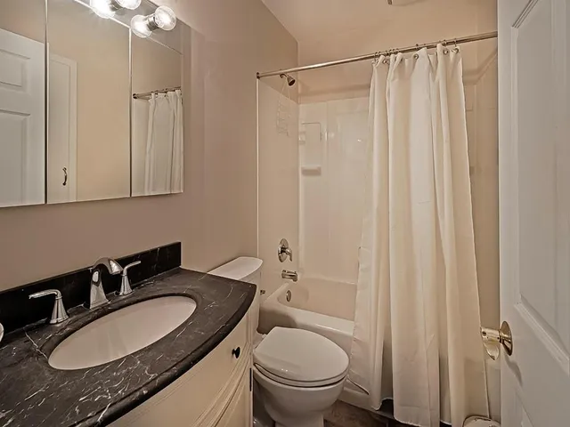 a bathroom with a granite countertop sink toilet a mirror a vanity and shower