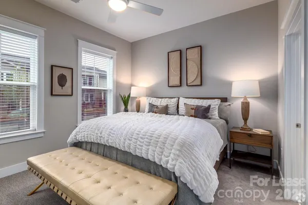 a bed sitting in a bedroom next to a window and a lamp