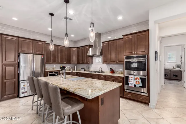 a kitchen with granite countertop a refrigerator a stove a kitchen island a sink and chairs