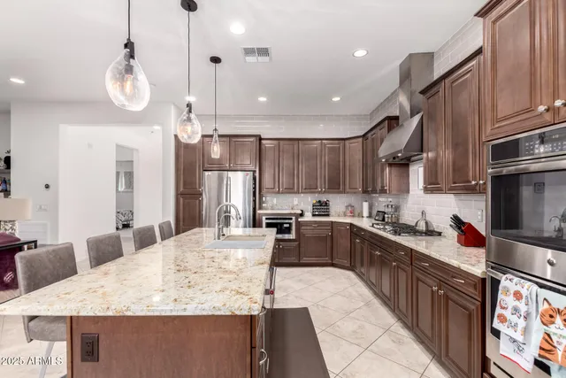 a kitchen with stainless steel appliances kitchen island granite countertop a sink refrigerator and cabinets