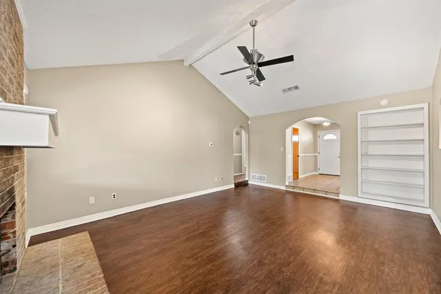 a view of an empty room with window and wooden floor