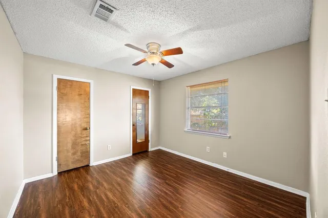 an empty room with wooden floor fan and windows