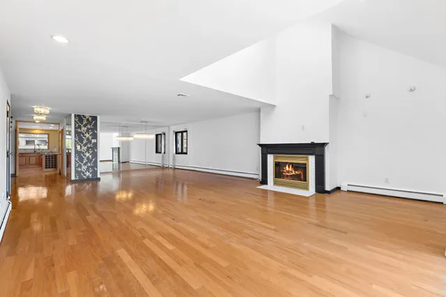 a view of empty room with wooden floor and a fireplace