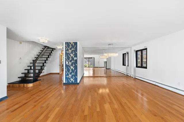 a view of an empty room with wooden floor and stairs