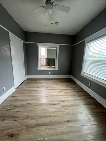 a view of an empty room with a window and wooden floor