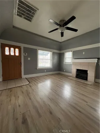 a view of empty room with wooden floor and fan