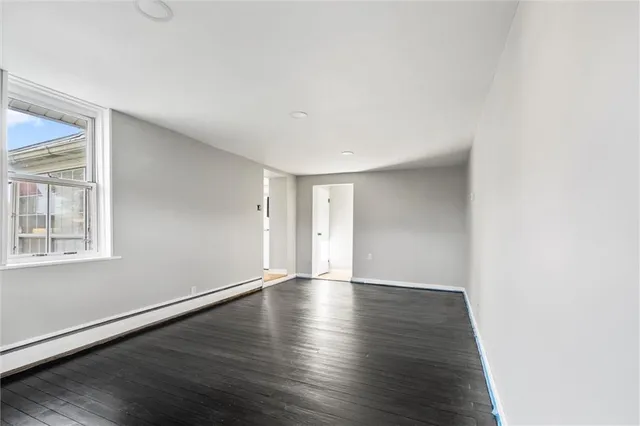 a view of an empty room with wooden floor and windows