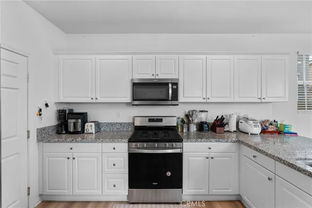 a kitchen with granite countertop white cabinets and stainless steel appliances