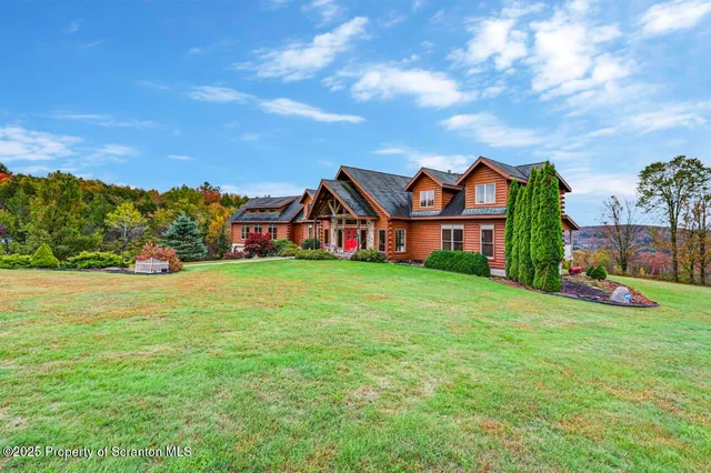 a view of a house with a big yard and large trees