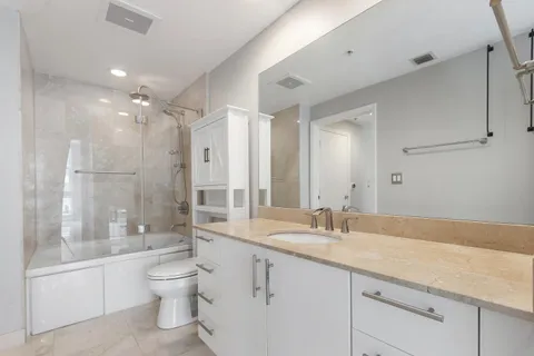 a bathroom with a granite countertop sink a toilet and shower