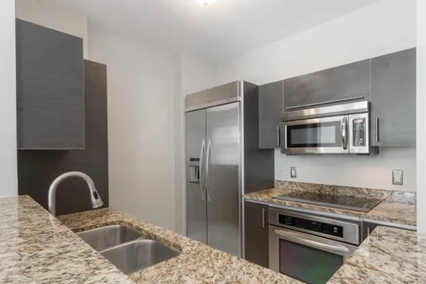 a kitchen with stainless steel appliances granite countertop a sink and a stove