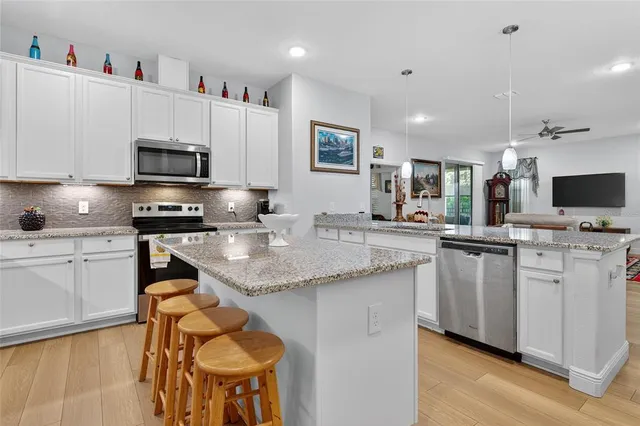 a kitchen with stainless steel appliances granite countertop a stove top oven a sink a microwave and a refrigerator
