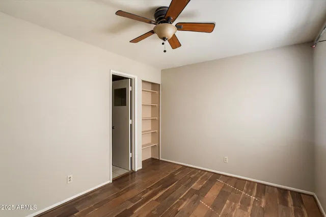 an empty room with a ceiling fan and wooden floor