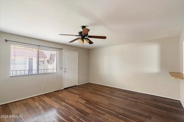 a view of empty room with wooden floor and fan