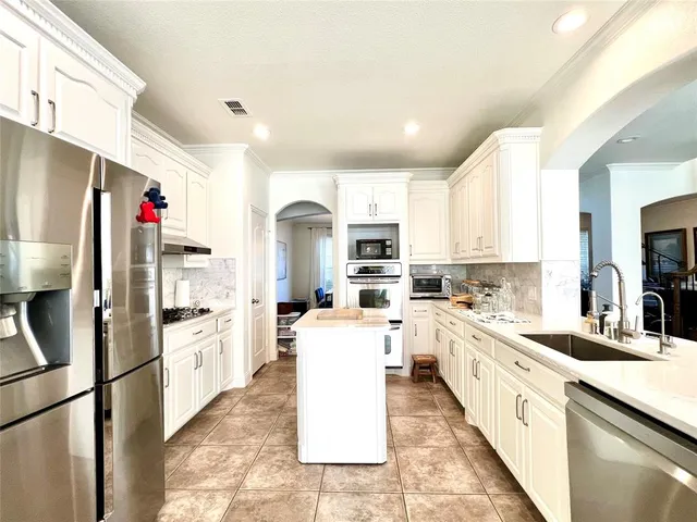a kitchen with white cabinets and stainless steel appliances
