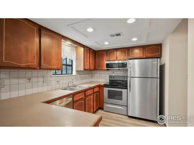 a kitchen with stainless steel appliances granite countertop a refrigerator a sink dishwasher a stove with wooden cabinets