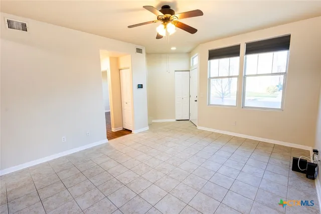 an empty room with windows and fan