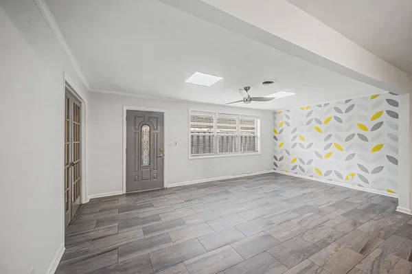 a view of an empty room with a window and wooden floor