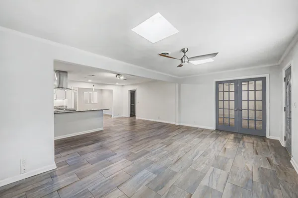 an empty room with wooden floor ceiling fan and windows