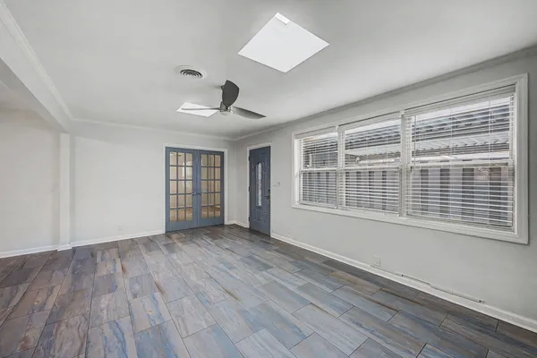 a view of an empty room with a window and wooden floor