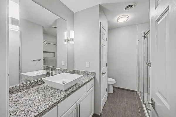 a bathroom with a granite countertop sink a toilet and shower