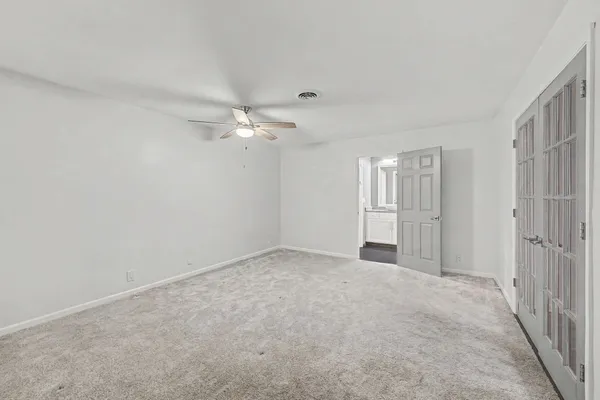 an empty room with windows and fan