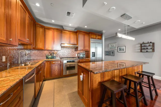 a kitchen with stainless steel appliances granite countertop a table chairs sink refrigerator and cabinets