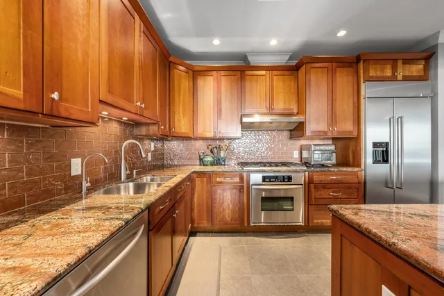 a kitchen with stainless steel appliances granite countertop a sink stove and refrigerator