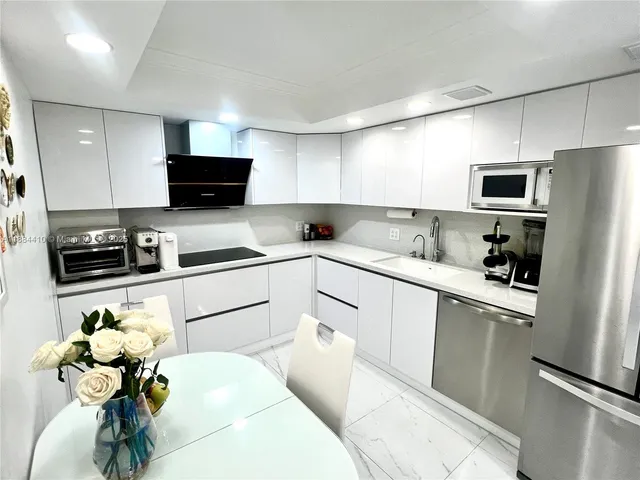 a kitchen with stainless steel appliances white cabinets a sink a stove and a refrigerator