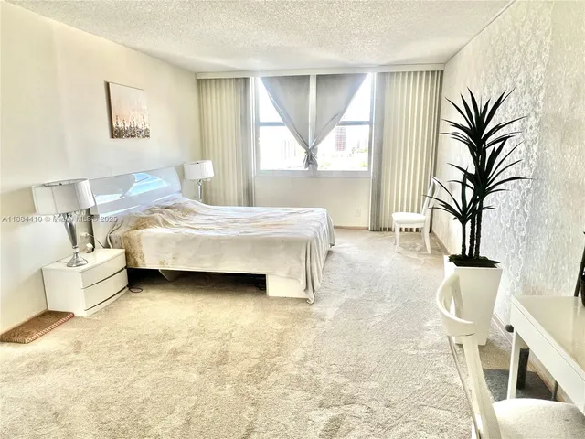 a bedroom with a large bed and a potted plant