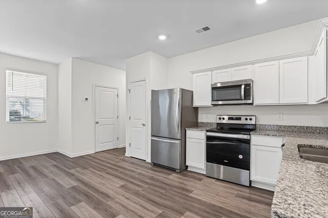 a kitchen with stainless steel appliances granite countertop a refrigerator microwave and stove top oven