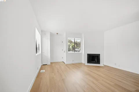 a view of empty room with wooden floor and fireplace