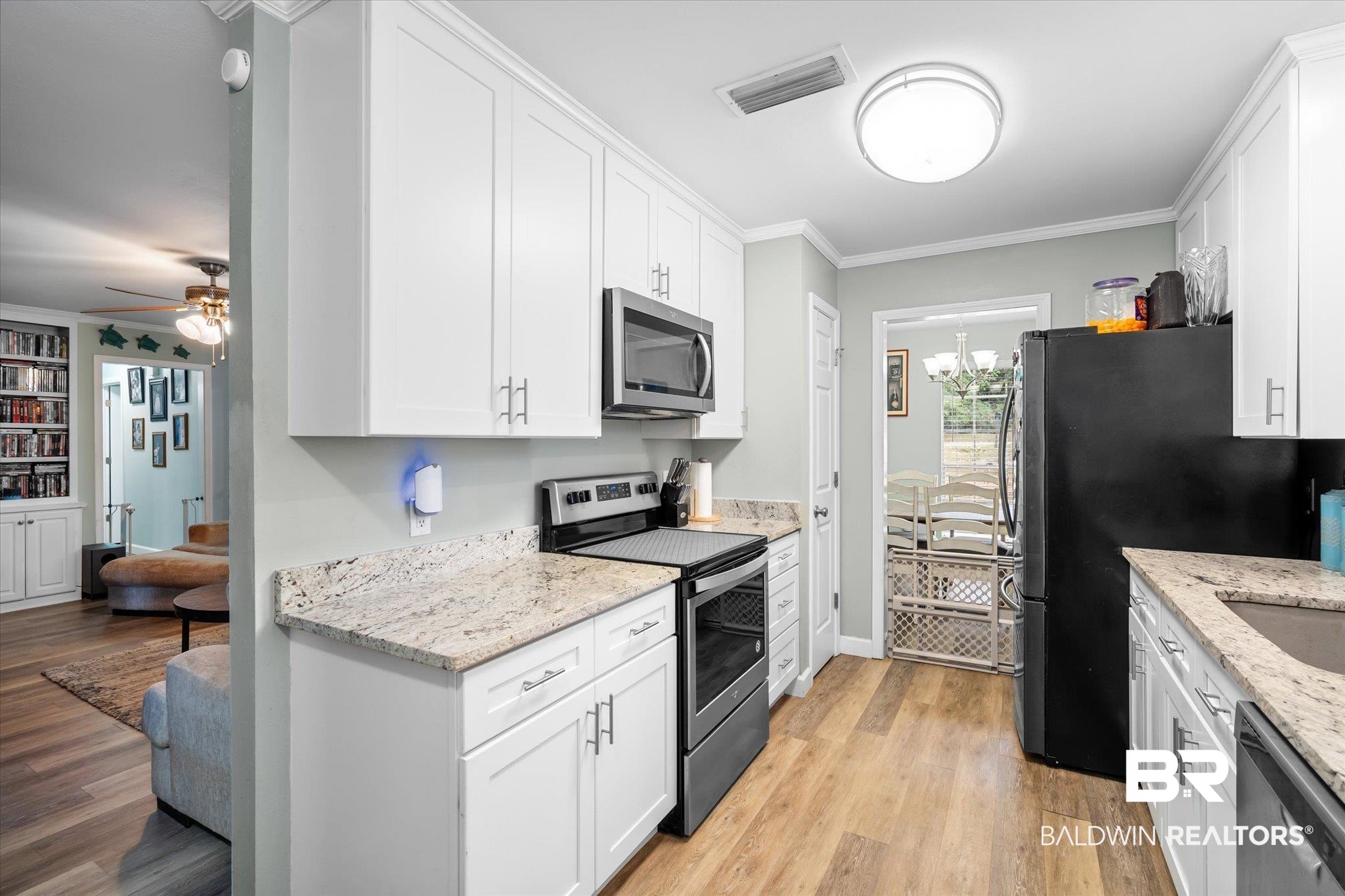 9987 Downing Street Semmes, AL 36575 - Photo 5 of 20 Kitchen featuring stainless steel appliances, light hardwood / wood-style floors, light stone counters, ornamental molding, and white cabinets