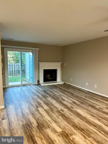 a view of empty room with wooden floor and fireplace