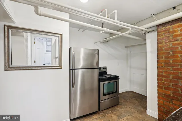 a view of a refrigerator in kitchen and an empty room