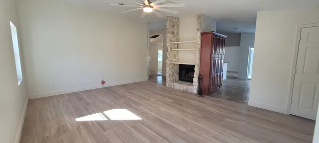 a view of empty room with wooden floor and fireplace