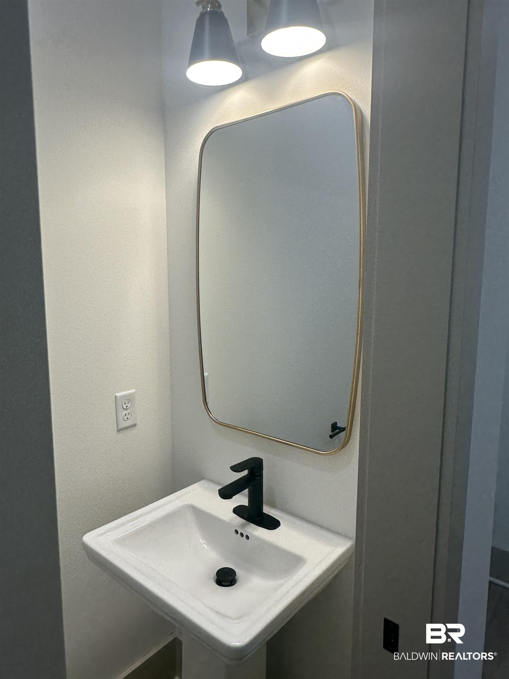 13111 Gopher Court Elberta, AL 36530 - Photo 27 of 41 Pedestal sink with matte black faucet, framed mirror, and dual overhead light fixtures