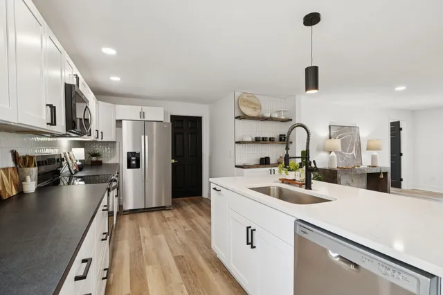 a kitchen with stainless steel appliances a sink a stove a refrigerator and cabinets