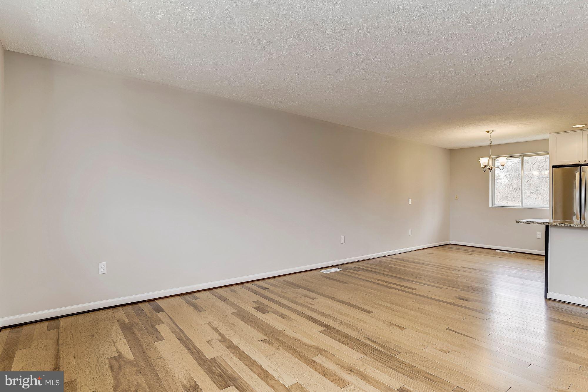 8614 Lugano Road Randallstown, MD 21133 - Photo 5 of 25 a view of an empty room with wooden floor and a window