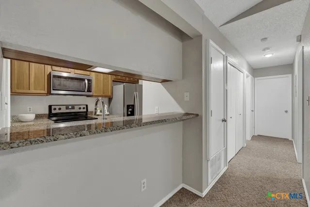 a kitchen with stainless steel appliances granite countertop a refrigerator a stove a sink dishwasher and wooden cabinets