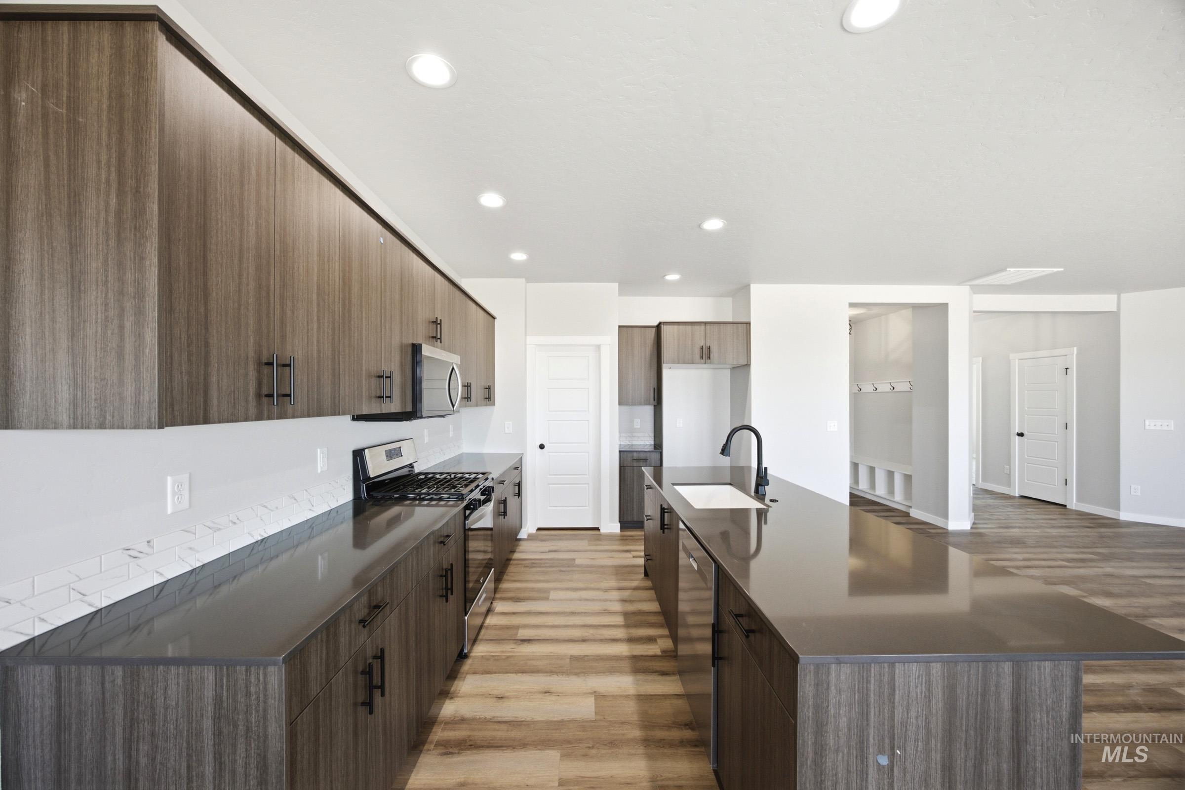 4344 East Rincon Drive Meridian, ID 83642 - Photo 5 of 26 Kitchen featuring a large island with an undermount sink, wood-finish cabinetry, stainless steel appliances, and wood-finish flooring
