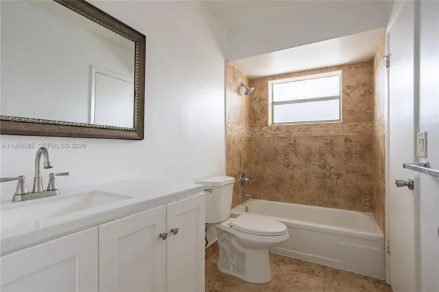 a bathroom with a toilet a sink a mirror a bathtub and vanity