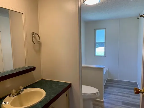 a bathroom with a granite countertop toilet a sink and mirror