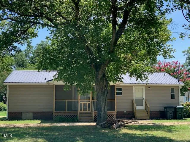 a backyard of a house with potted plants and large tree