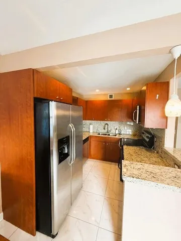 a large kitchen with stainless steel appliances kitchen island granite countertop a refrigerator and a stove