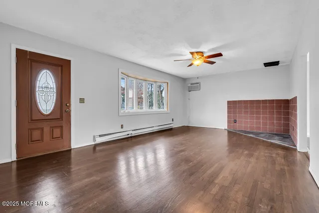 a view of an empty room with window and wooden floor