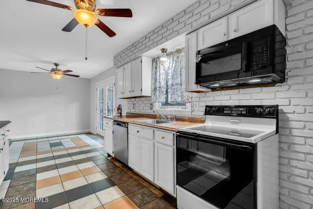 a kitchen with stainless steel appliances white cabinets granite counter tops and a window
