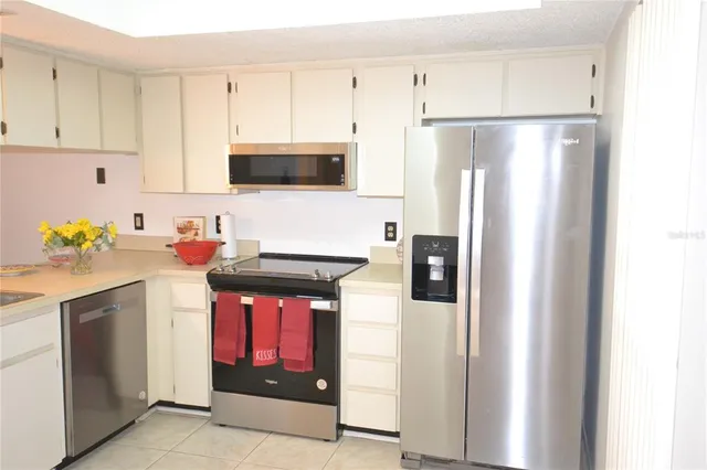 a kitchen with stainless steel appliances granite countertop a refrigerator a stove a microwave oven with white cabinets